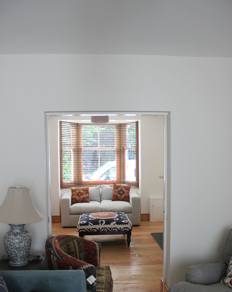 Modelo de salón para visitas abierto bohemio de tamaño medio con paredes blancas, suelo de madera clara, todas las chimeneas, marco de chimenea de baldosas y/o azulejos y televisor colgado en la pared