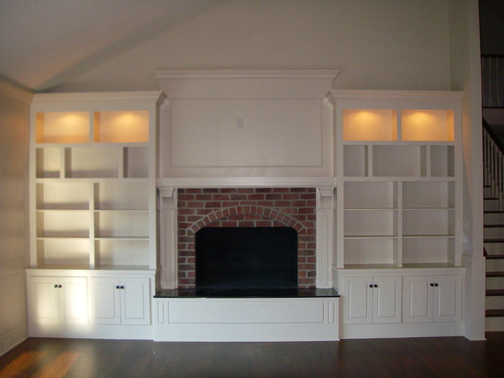 Cette photo montre un grand salon chic ouvert avec une bibliothèque ou un coin lecture, un mur blanc, parquet foncé, une cheminée standard, un manteau de cheminée en plâtre et aucun téléviseur.