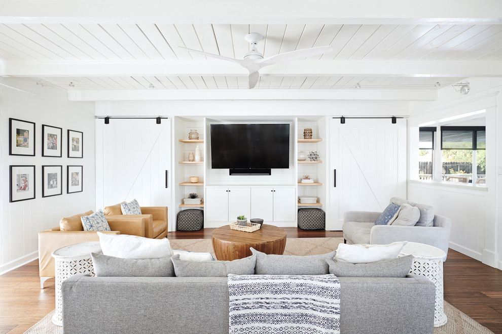 Immagine di un soggiorno stile marinaro con pareti bianche, parquet scuro, parete attrezzata e pavimento marrone