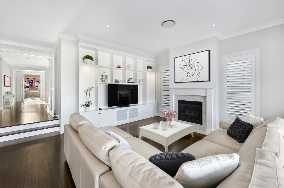 Cette photo montre un grand salon chic ouvert avec un mur blanc, parquet foncé, une cheminée standard, un manteau de cheminée en brique, un téléviseur indépendant et un sol marron.