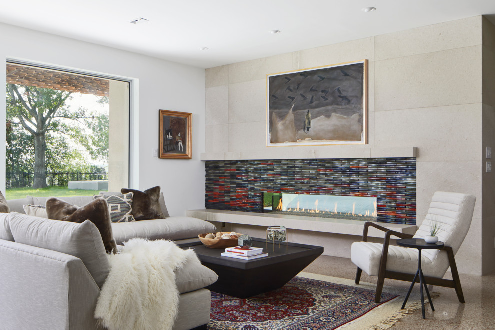 Modelo de salón abierto actual grande sin televisor con chimenea lineal, marco de chimenea de baldosas y/o azulejos, paredes blancas y suelo gris