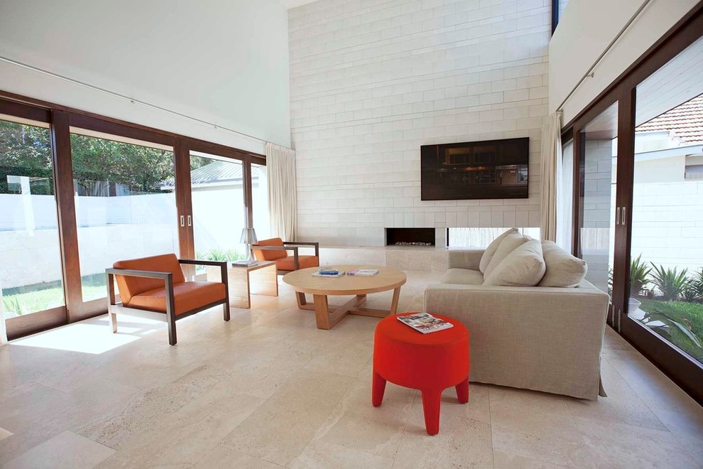 Идея дизайна: огромная парадная, двухуровневая гостиная комната в современном стиле с серыми стенами, полом из травертина, отдельно стоящим телевизором, горизонтальным камином и фасадом камина из камня