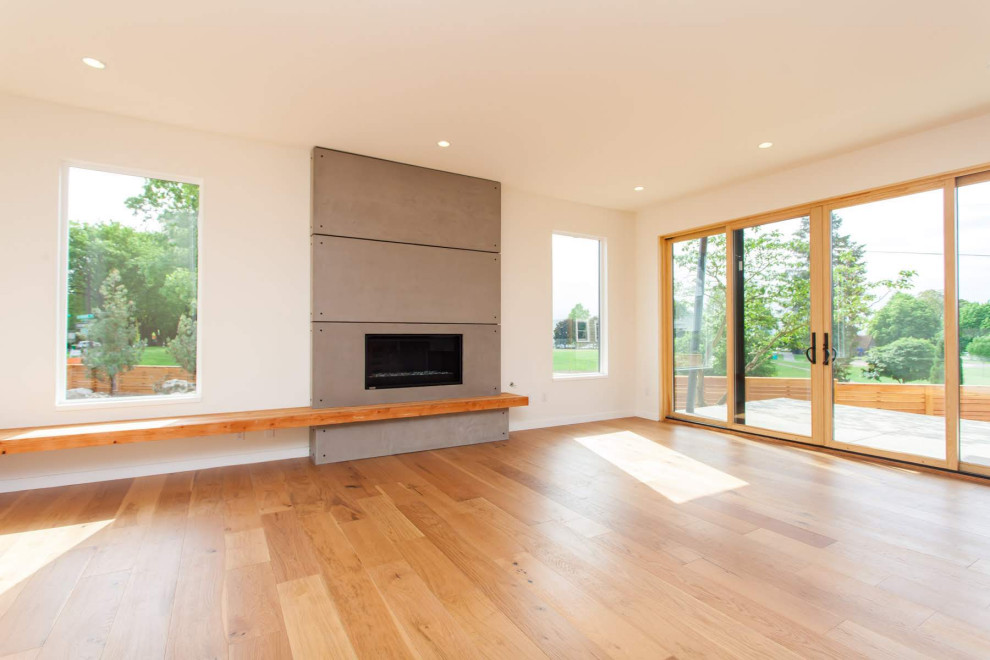 This is an example of a medium sized modern formal enclosed living room in Portland with white walls, light hardwood flooring, a standard fireplace, a concrete fireplace surround, no tv and brown floors.