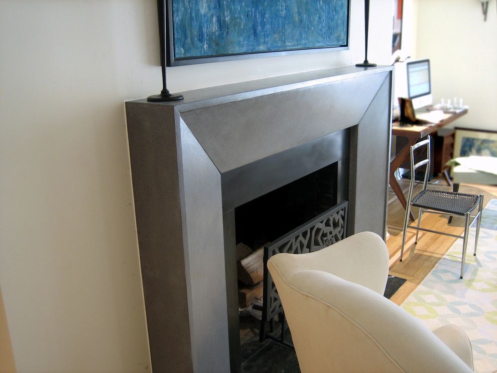 Photo of a contemporary living room in New York with a concrete fireplace surround.