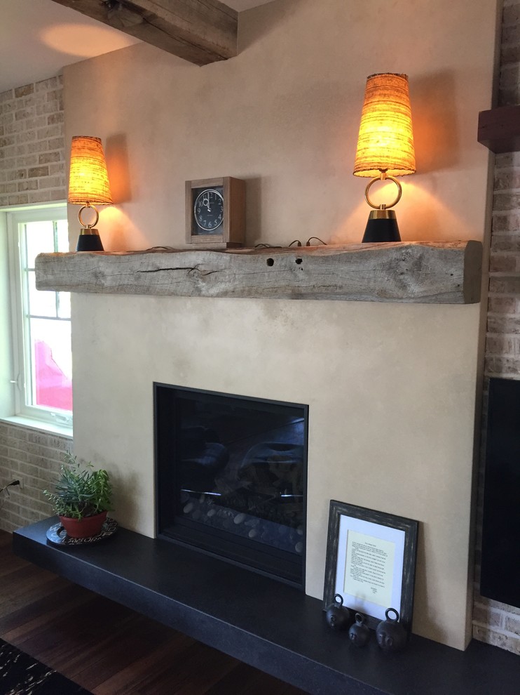 Foto di un soggiorno design con parquet scuro, camino classico, cornice del camino in cemento e TV a parete