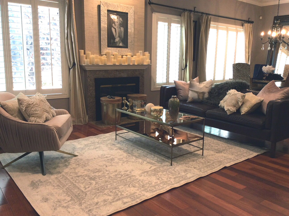 Cette image montre un salon bohème de taille moyenne et ouvert avec une cheminée standard, un manteau de cheminée en pierre, un téléviseur fixé au mur, un sol marron, un mur gris et un sol en bois brun.