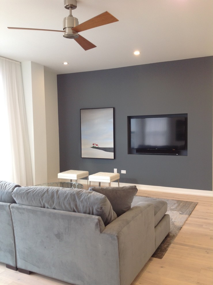 Cette photo montre un petit salon tendance ouvert avec un mur bleu, parquet clair et un téléviseur fixé au mur.