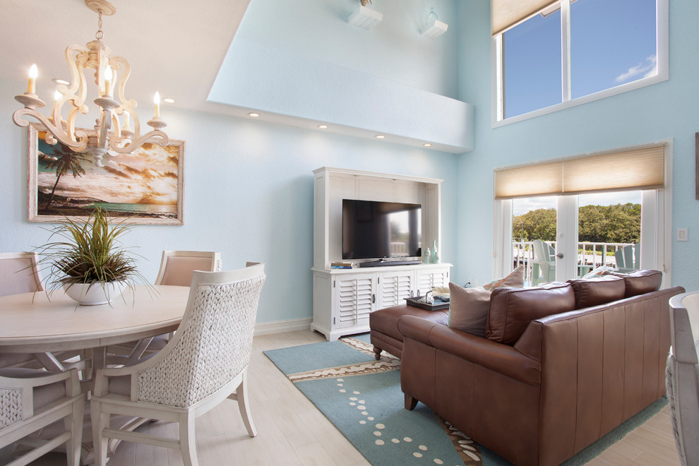Aménagement d'un salon bord de mer de taille moyenne et ouvert avec un mur bleu, aucune cheminée, un téléviseur indépendant et un sol beige.