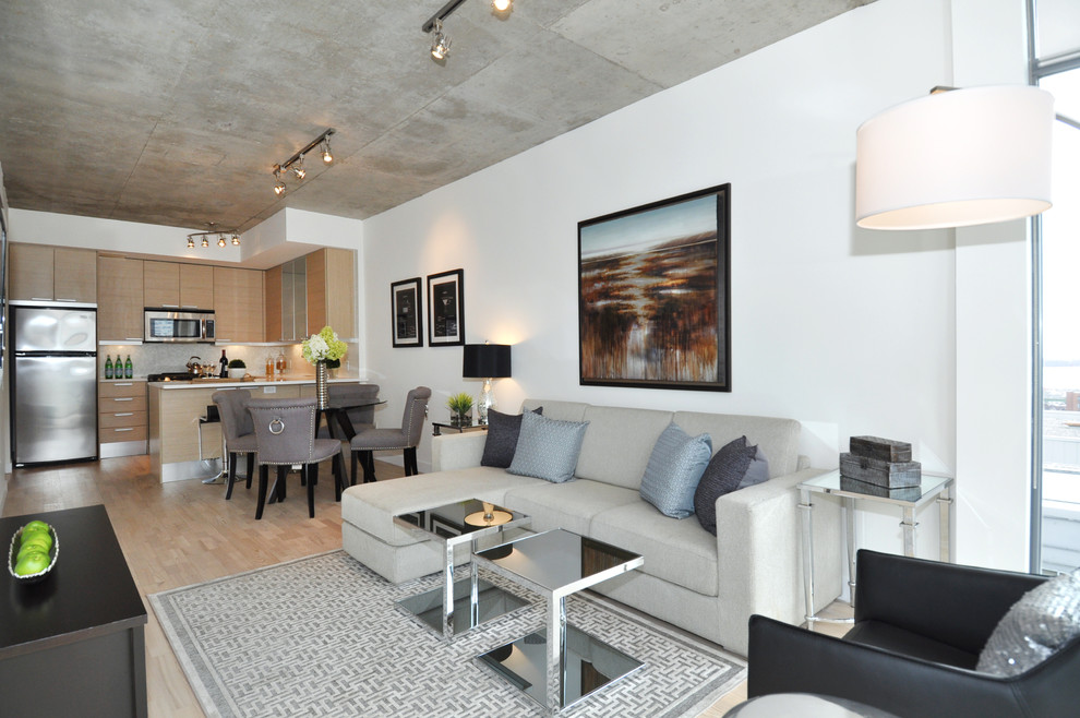 Diseño de salón para visitas abierto contemporáneo sin chimenea con paredes grises, suelo de madera clara y televisor colgado en la pared