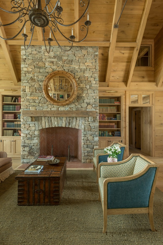 Cette photo montre un grand salon montagne fermé avec une bibliothèque ou un coin lecture, un mur marron, parquet clair, une cheminée standard, un manteau de cheminée en pierre, aucun téléviseur et un sol marron.