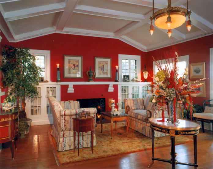 デンバーにある高級な広いトラディショナルスタイルのおしゃれなリビング (赤い壁、無垢フローリング、標準型暖炉、漆喰の暖炉まわり) の写真