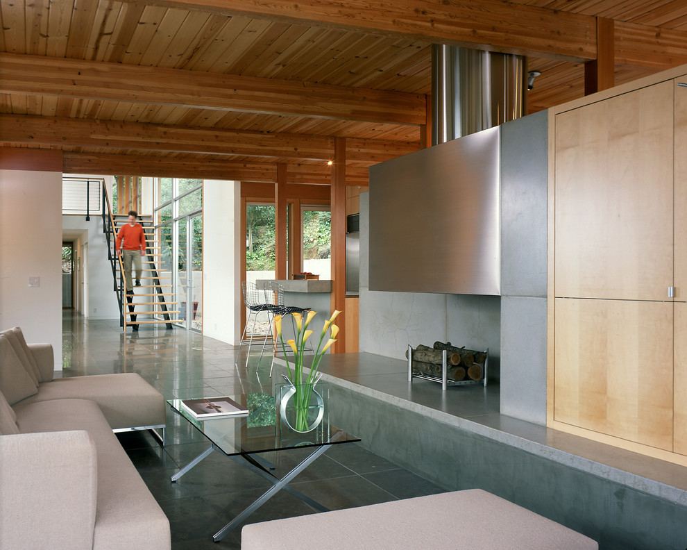 Modelo de salón abierto minimalista de tamaño medio con marco de chimenea de metal, paredes blancas y televisor retractable