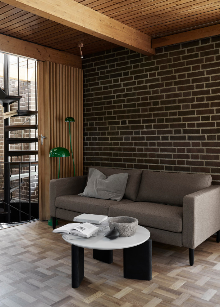 На фото: гостиная комната в стиле ретро с паркетным полом среднего тона, стандартным камином, фасадом камина из кирпича, балками на потолке и кирпичными стенами с