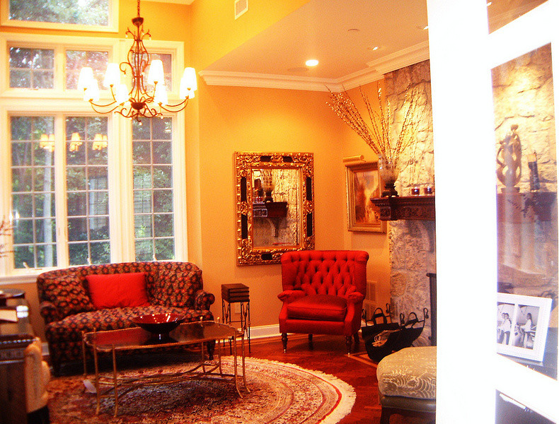 Пример оригинального дизайна: изолированная гостиная комната среднего размера в классическом стиле с музыкальной комнатой, оранжевыми стенами, паркетным полом среднего тона, стандартным камином и фасадом камина из камня без телевизора