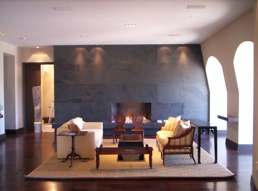 Cette image montre un salon bohème avec un mur beige, parquet foncé, une cheminée ribbon et un manteau de cheminée en pierre.