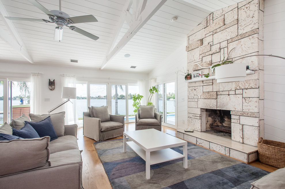 Inspiration for a large beach style open plan living room in Tampa with white walls, light hardwood flooring, a standard fireplace, a stone fireplace surround, no tv and beige floors.