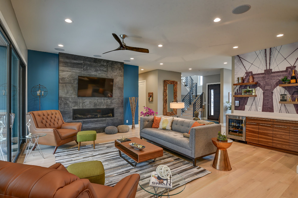 This is an example of a large contemporary open plan living room in Indianapolis with a home bar, light hardwood flooring, a standard fireplace, a tiled fireplace surround and a wall mounted tv.