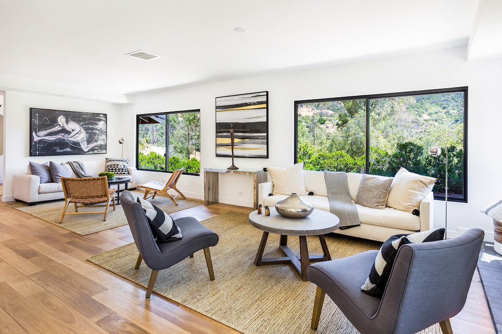 Example of a trendy open concept light wood floor and beige floor living room design in Los Angeles with white walls