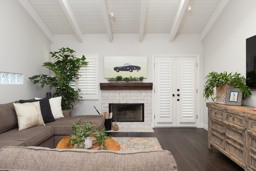 Modernes Wohnzimmer mit weißer Wandfarbe, dunklem Holzboden, Kaminumrandung aus Backstein und weißem Boden in Orange County