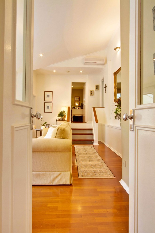 Foto de salón para visitas cerrado, abovedado y blanco clásico renovado grande con paredes blancas, suelo de madera en tonos medios y suelo marrón