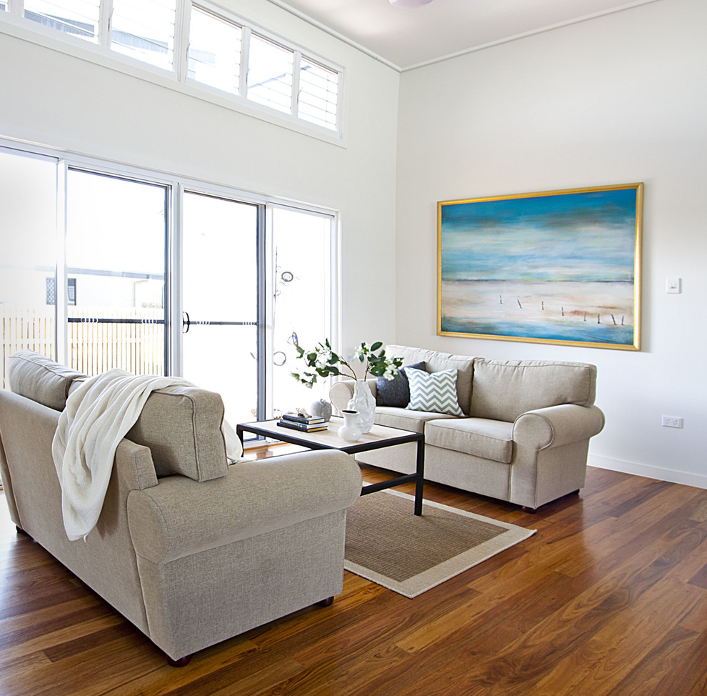 Design ideas for a coastal living room in Brisbane with white walls and medium hardwood flooring.