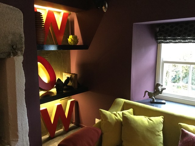 Cette image montre un salon design de taille moyenne et fermé avec un mur violet, parquet foncé, un poêle à bois, un manteau de cheminée en pierre et un téléviseur fixé au mur.