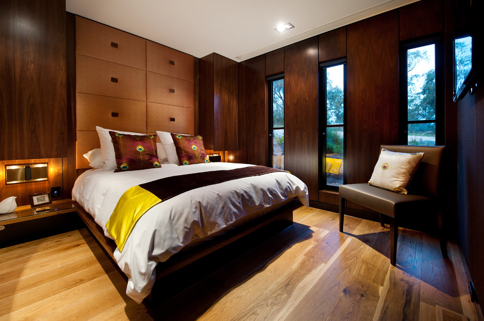 Esempio di una camera da letto minimal di medie dimensioni con pareti marroni, pavimento in legno massello medio e camino classico