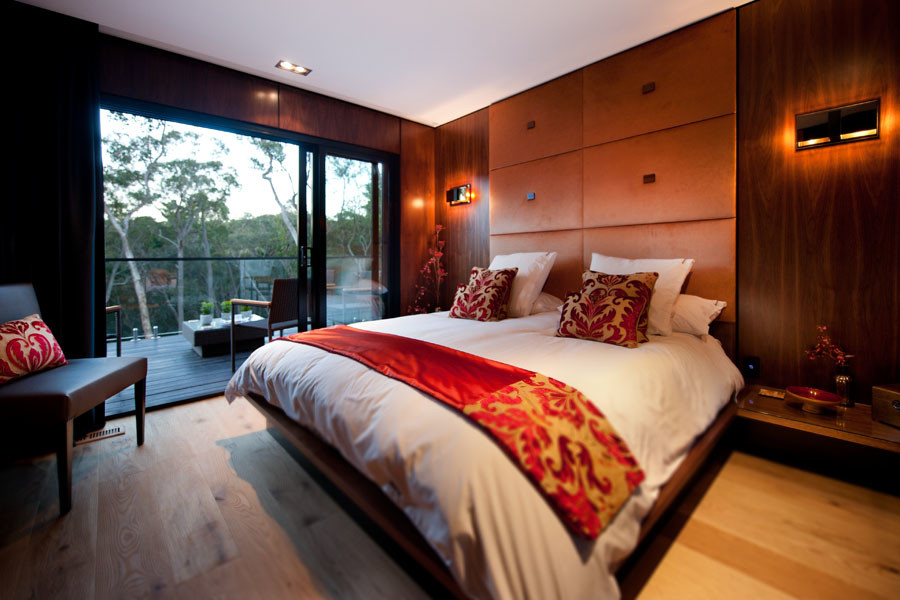 Foto di una camera da letto design di medie dimensioni con pareti marroni, pavimento in legno massello medio e camino classico