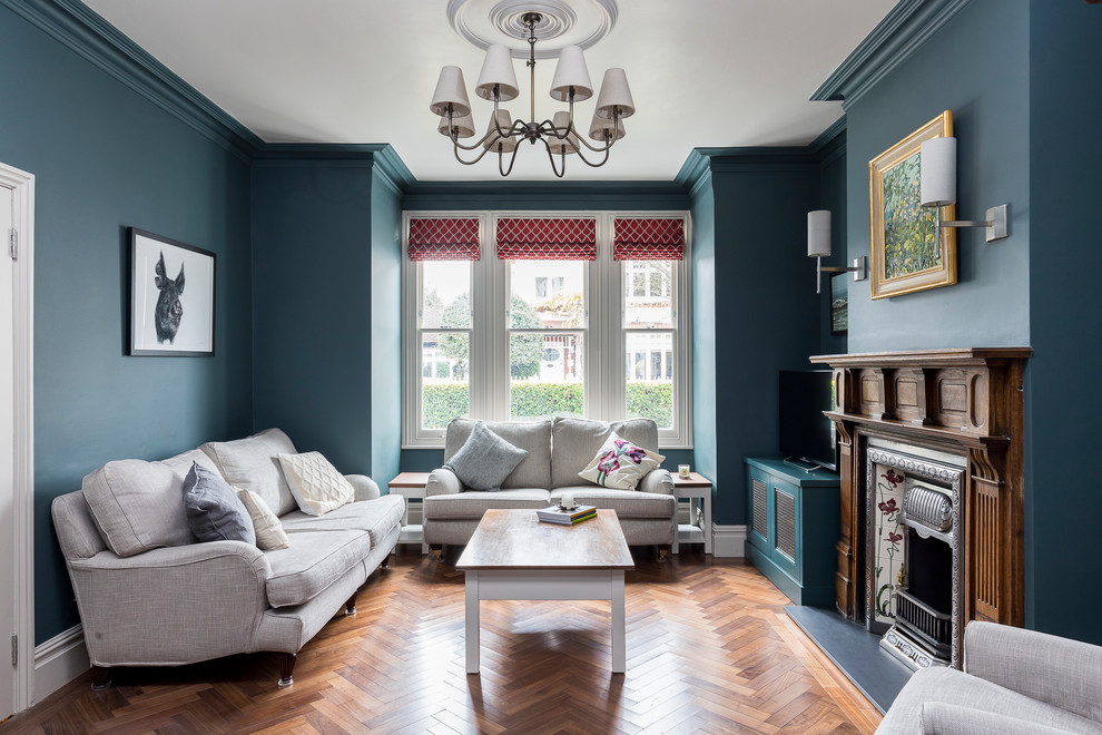 This is an example of a traditional formal and grey and teal enclosed living room in London with green walls, medium hardwood flooring, a standard fireplace, a freestanding tv and brown floors.