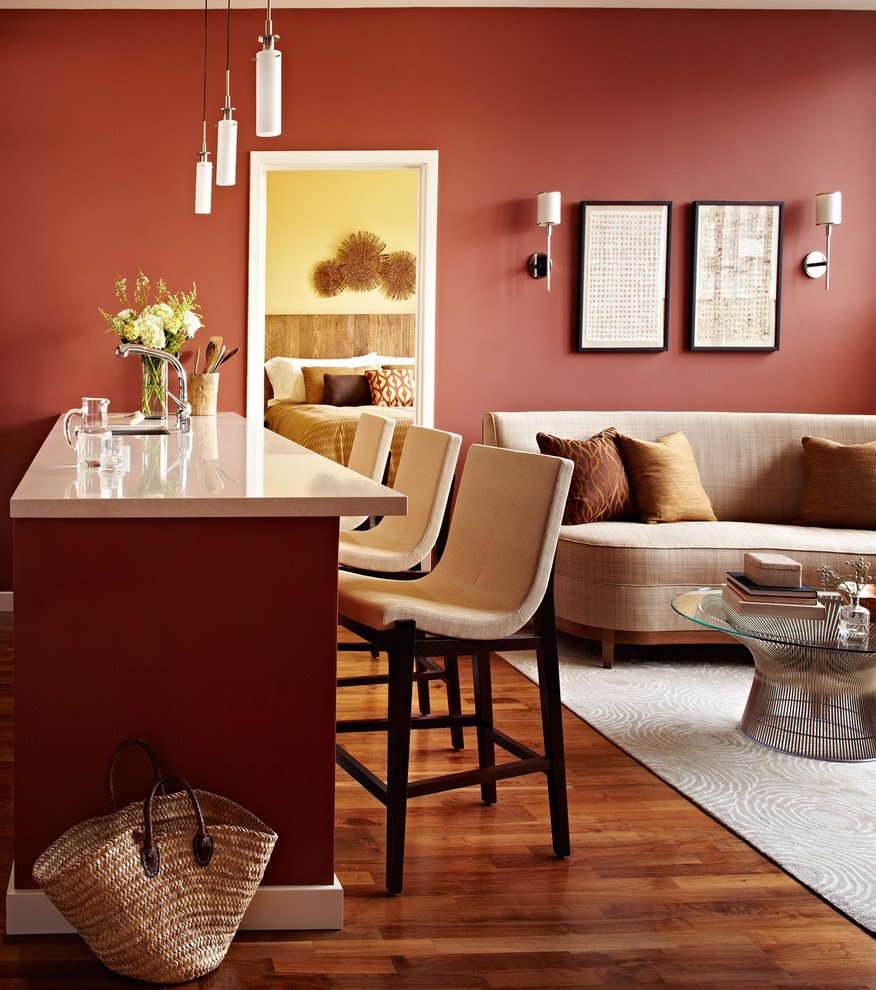 Cette photo montre un petit salon tendance avec un bar de salon, un mur rouge, un sol en bois brun et un téléviseur fixé au mur.
