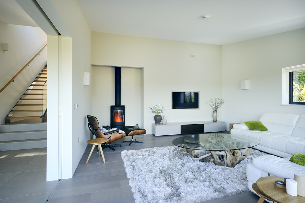 Ispirazione per un soggiorno minimal di medie dimensioni e chiuso con pareti gialle, stufa a legna, TV a parete e pavimento grigio