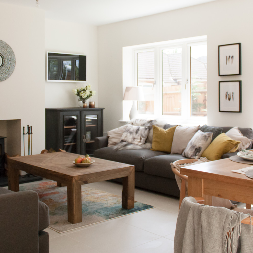 This is an example of a medium sized modern open plan living room in Hertfordshire with white walls, porcelain flooring, a wood burning stove, a plastered fireplace surround and beige floors.