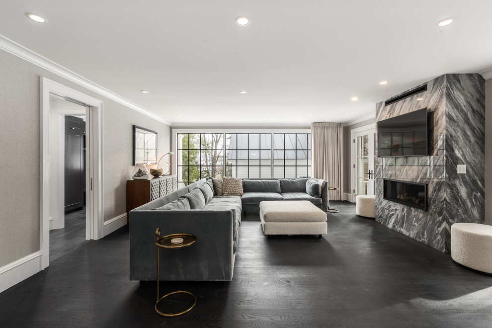 Large trendy open concept dark wood floor and black floor living room photo in New York with gray walls, a standard fireplace, a stone fireplace and a wall-mounted tv