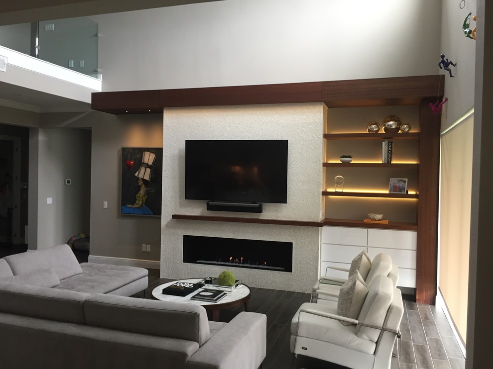 На фото: огромная гостиная комната в современном стиле с горизонтальным камином, фасадом камина из плитки, телевизором на стене и черным полом с
