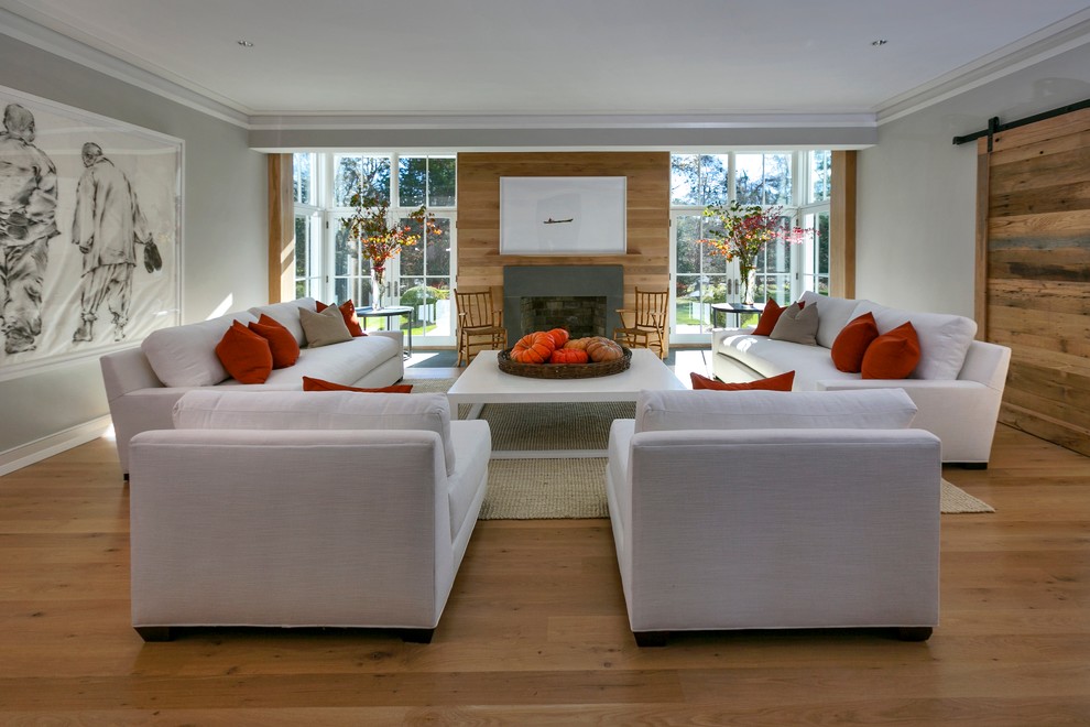 This is an example of a medium sized contemporary formal enclosed living room in New York with a concrete fireplace surround, white walls, light hardwood flooring, a standard fireplace and no tv.