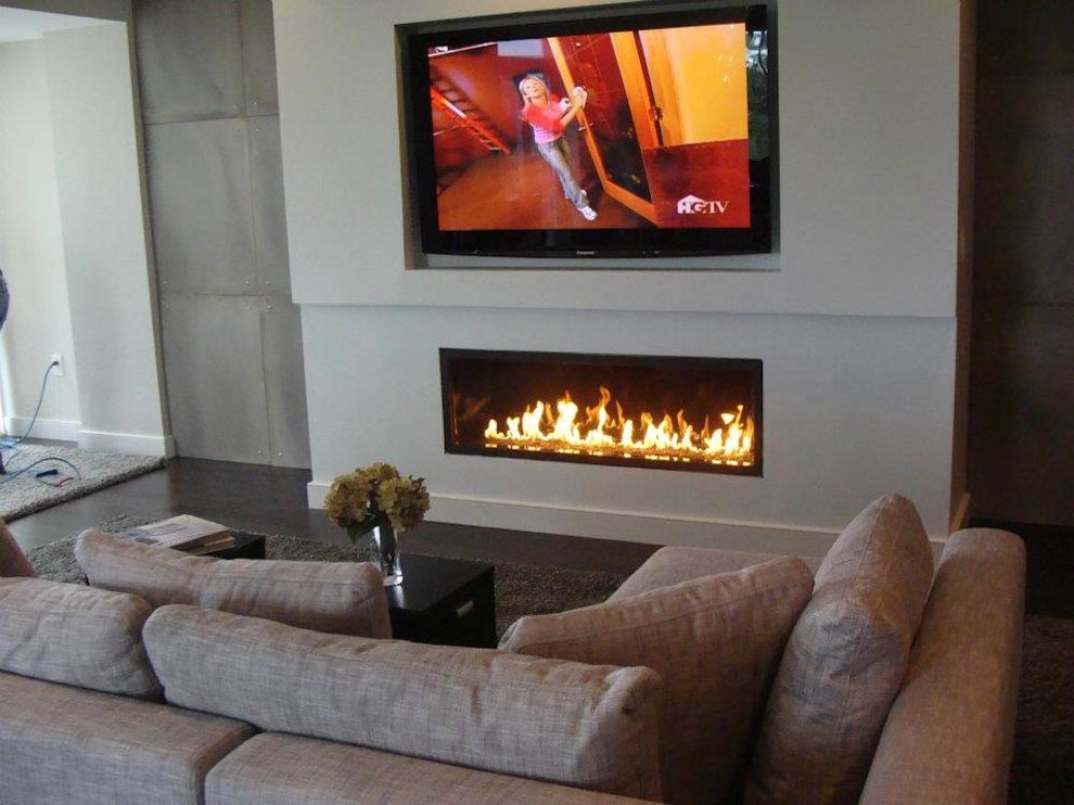 Imagen de salón actual con paredes grises, suelo de madera oscura, chimenea lineal y televisor colgado en la pared