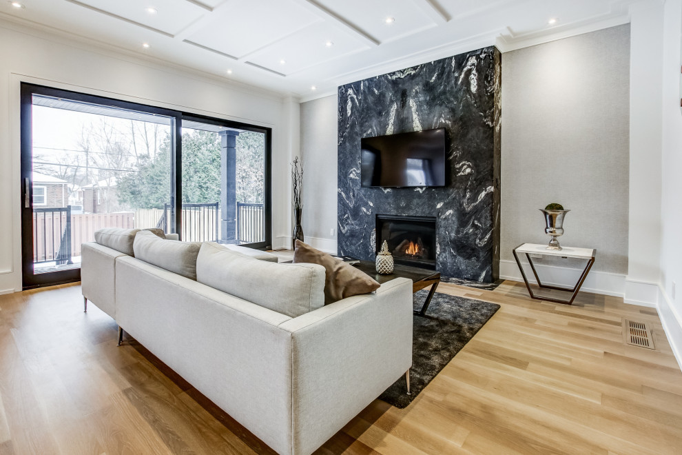 Large contemporary open plan living room in Toronto with grey walls, medium hardwood flooring, a standard fireplace, a stone fireplace surround, a wall mounted tv and brown floors.