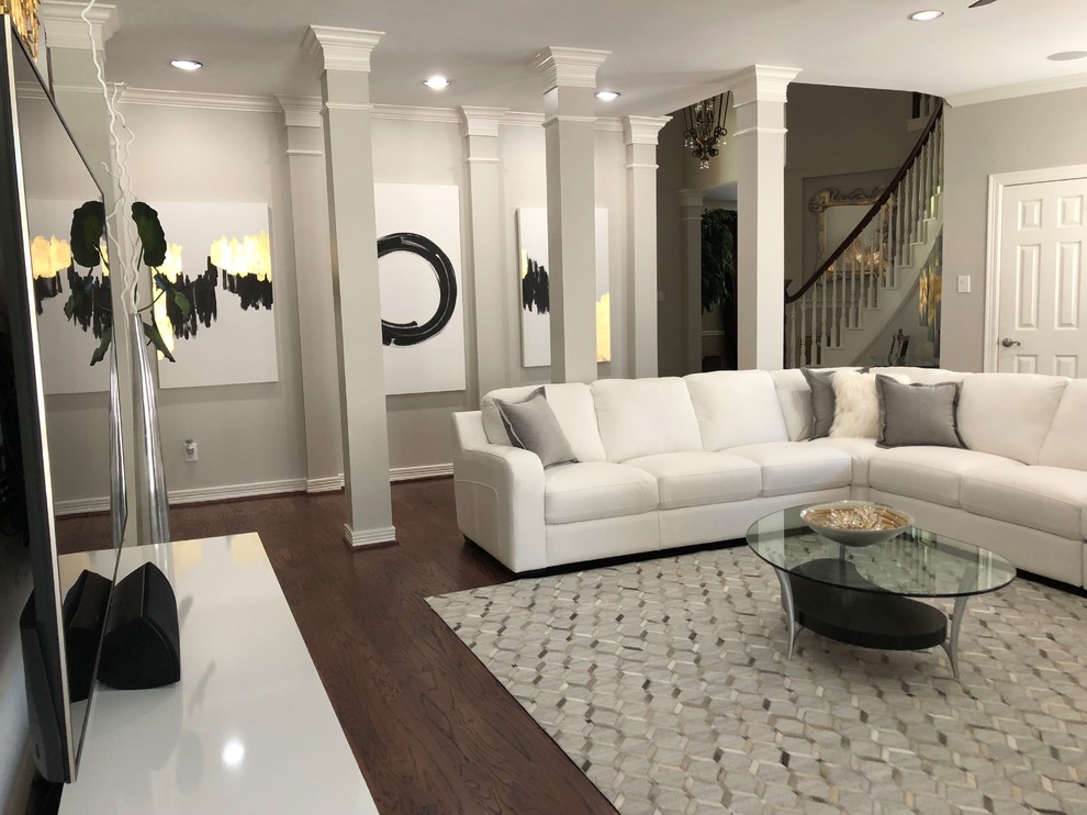 Источник вдохновения для домашнего уюта: большая изолированная гостиная комната в современном стиле с серыми стенами, темным паркетным полом, телевизором на стене и коричневым полом без камина