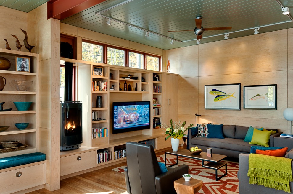 Modernes Wohnzimmer mit braunem Holzboden, Multimediawand und Kaminofen in Burlington