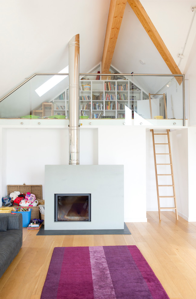 Foto på ett minimalistiskt loftrum, med vita väggar, ljust trägolv, en öppen vedspis, en spiselkrans i gips och brunt golv
