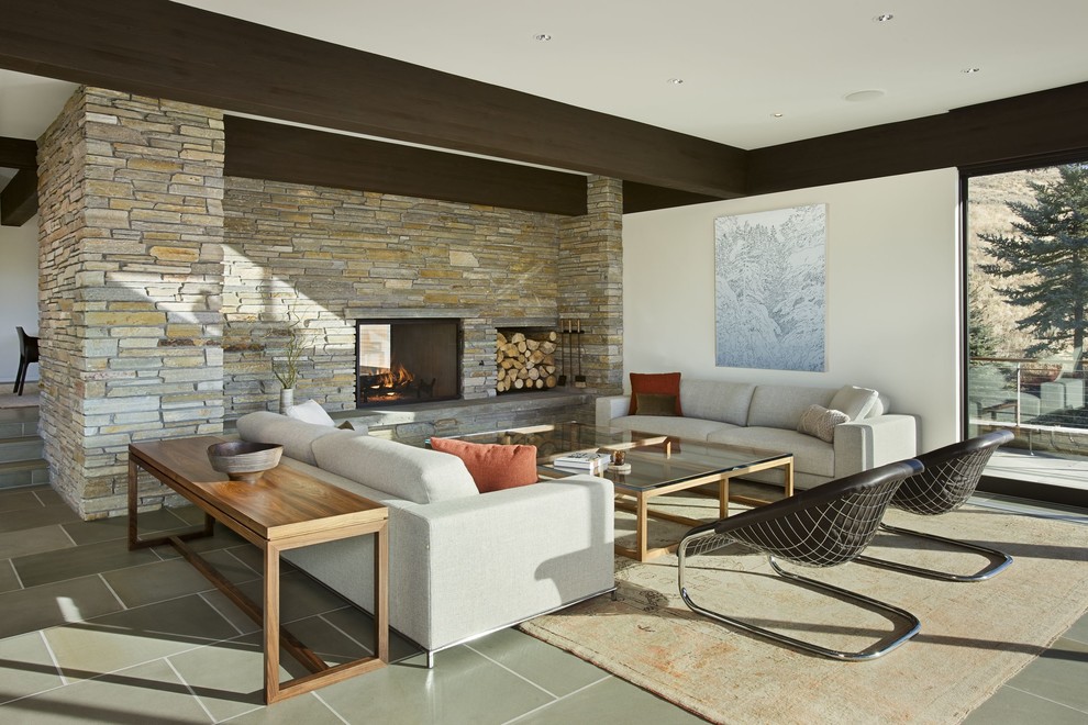 Idées déco pour un salon contemporain avec un mur blanc, une cheminée double-face, un manteau de cheminée en pierre et un mur en pierre.