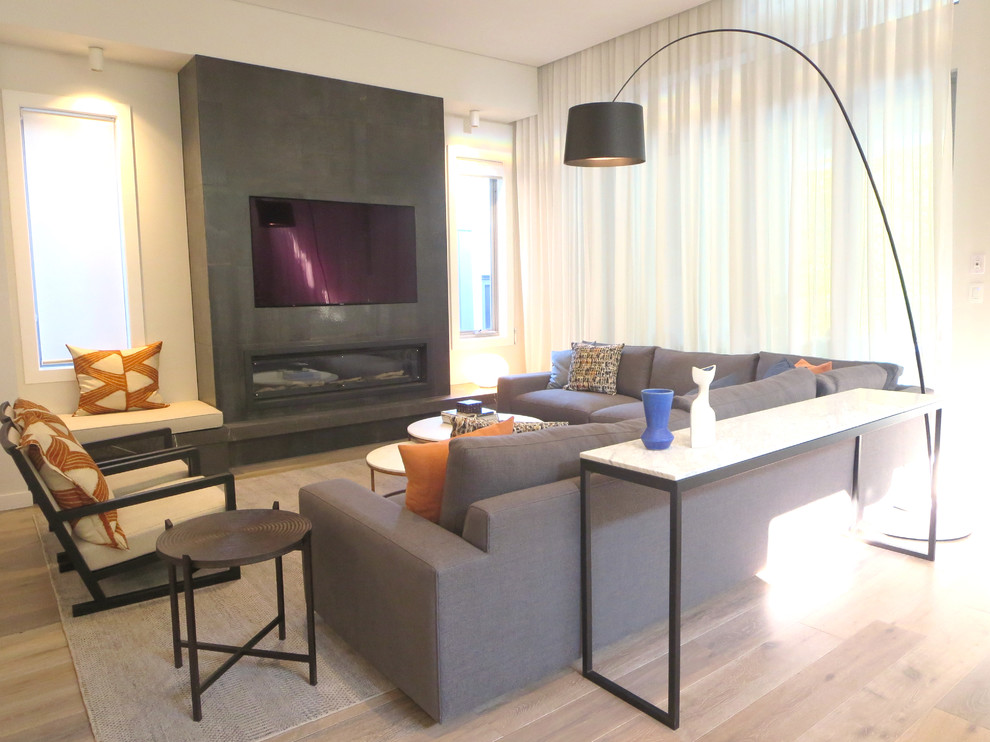 Aménagement d'un grand salon contemporain ouvert avec un sol en bois brun, un manteau de cheminée en carrelage, un téléviseur encastré et un sol marron.