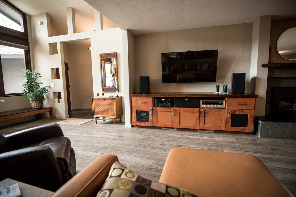 Источник вдохновения для домашнего уюта: большая открытая, объединенная гостиная комната в современном стиле с бежевыми стенами, фасадом камина из плитки, телевизором на стене, полом из ламината, стандартным камином и коричневым полом