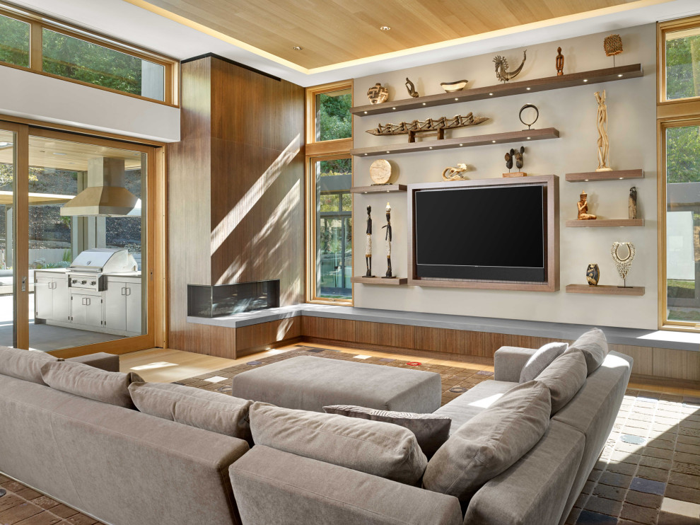 Foto på ett funkis allrum med öppen planlösning, med vita väggar, mellanmörkt trägolv, en bred öppen spis, en spiselkrans i trä, en väggmonterad TV och brunt golv