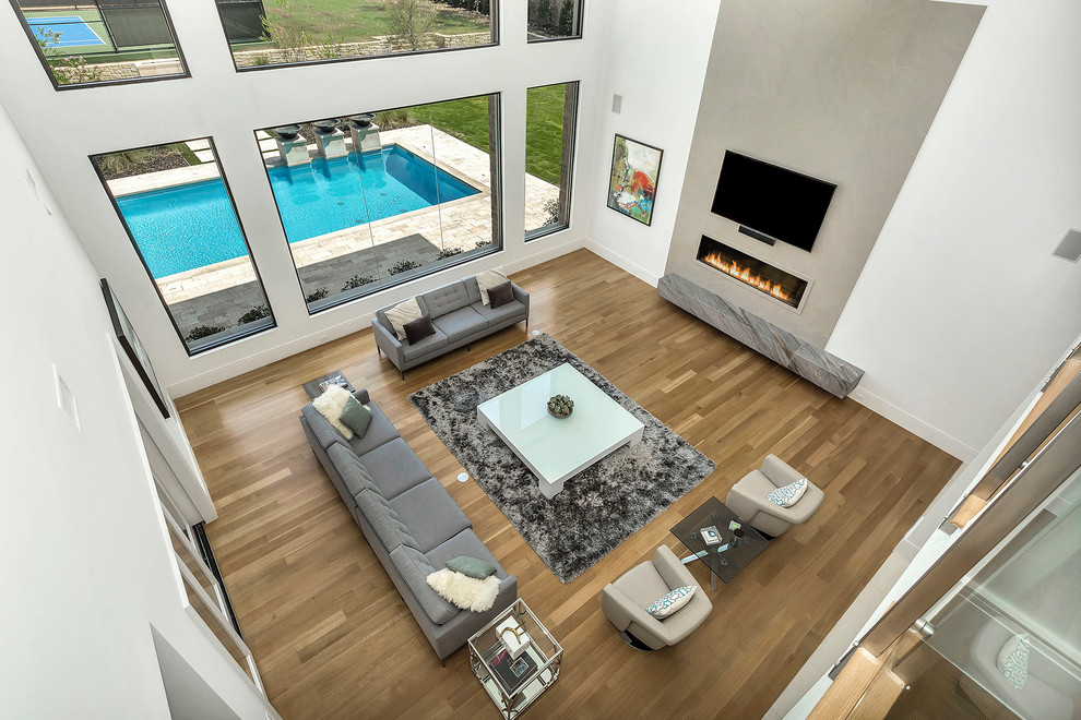 Источник вдохновения для домашнего уюта: огромная открытая гостиная комната в современном стиле с серыми стенами, светлым паркетным полом, телевизором на стене и коричневым полом