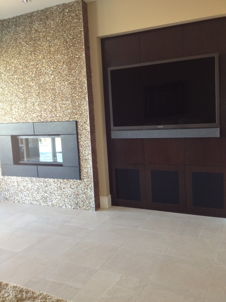 Ejemplo de salón con barra de bar abierto actual grande con paredes beige, suelo de travertino, chimenea lineal, marco de chimenea de metal y televisor colgado en la pared