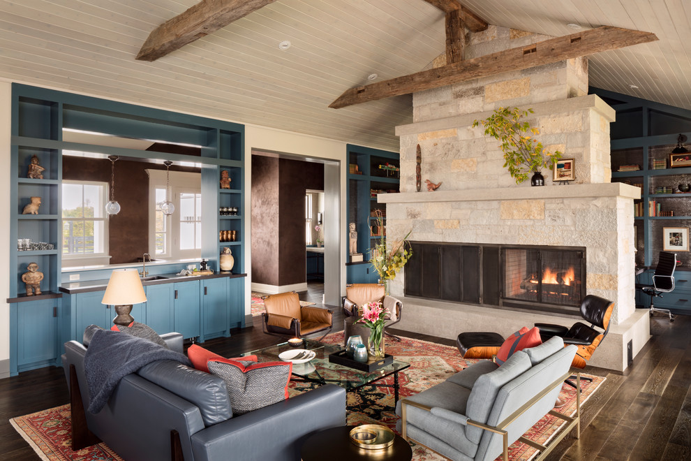 Idee per un grande soggiorno tradizionale con pareti blu, pavimento in legno massello medio, camino bifacciale, cornice del camino in pietra e pavimento marrone