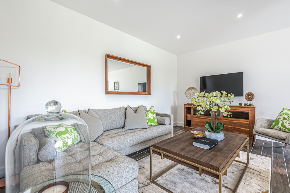Modernes Wohnzimmer mit weißer Wandfarbe, TV-Wand und braunem Boden in Hampshire