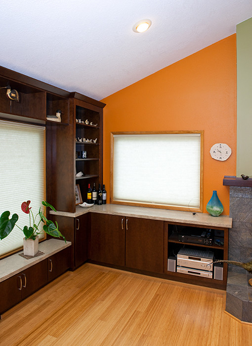 Example of a mid-sized trendy open concept light wood floor living room library design in Portland with orange walls, a wood stove, a stone fireplace and a wall-mounted tv