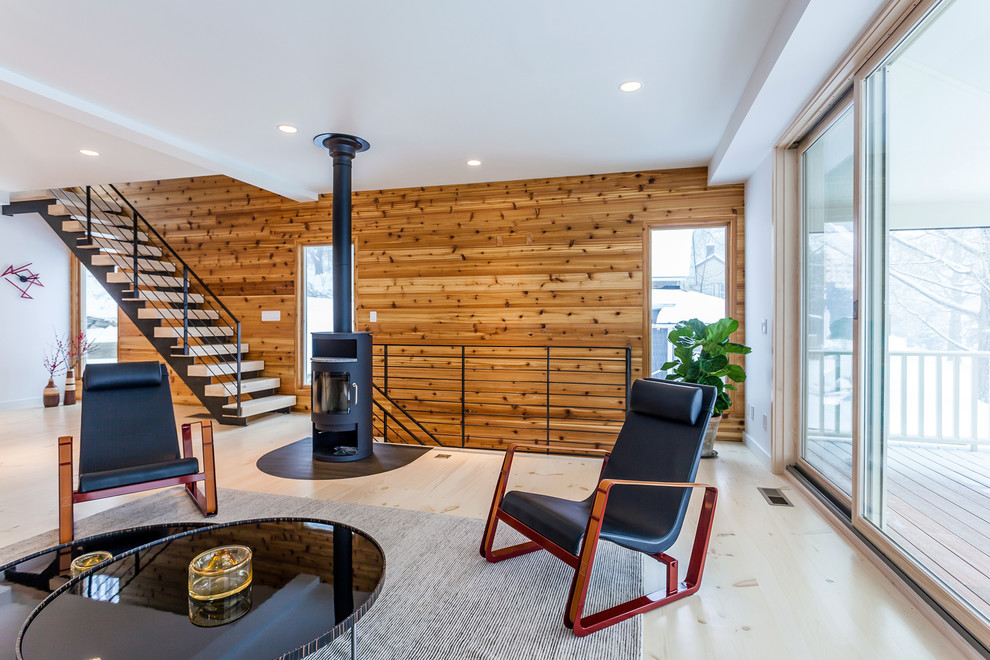Immagine di un grande soggiorno minimal aperto con pareti bianche, parquet chiaro e stufa a legna